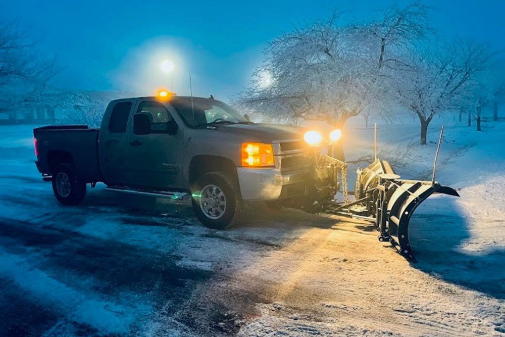 truck with snow plow and lights clearing snow